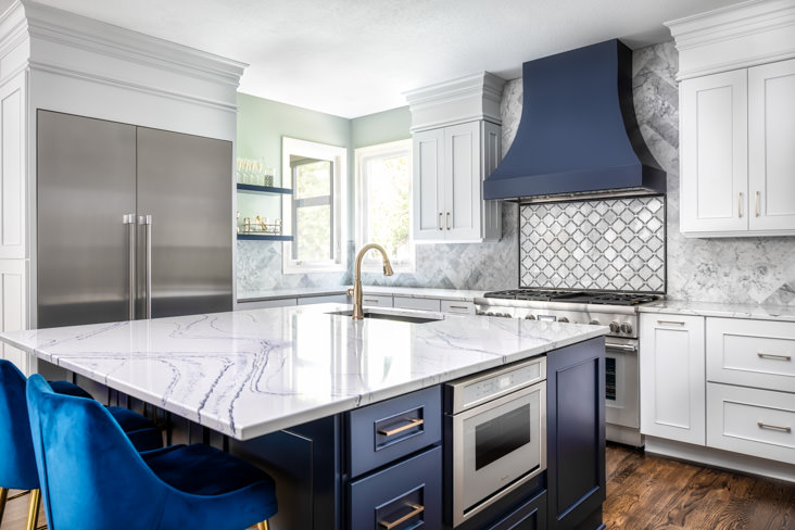 The navy blue and white cabinets with the pop of brass fixtures convey the overall elegance and beauty of this kitchen remodel